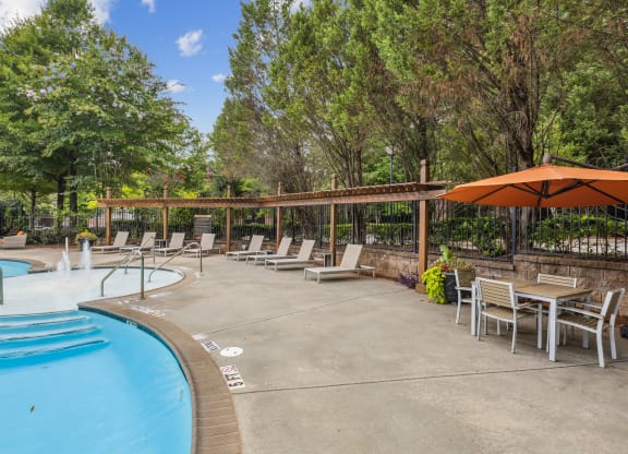 a resort style pool with chairs and tables and umbrellas
