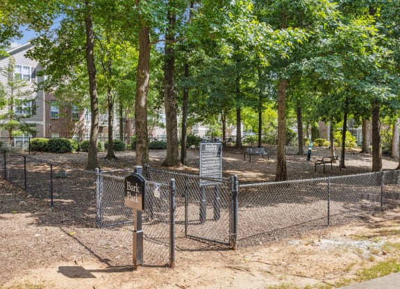 a fenced in park with trees and a sign on a fence