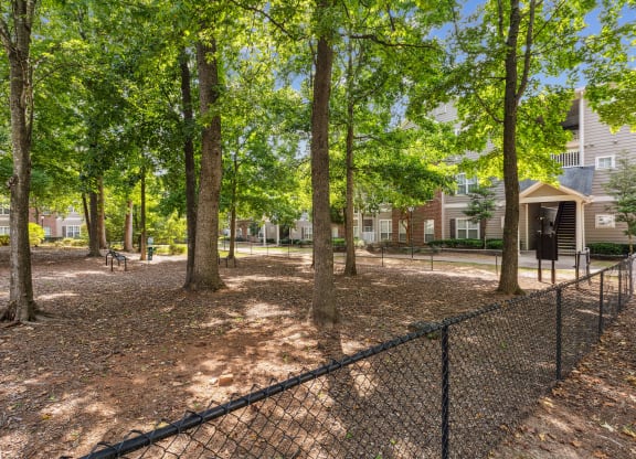 a fenced in dog park with trees and houses