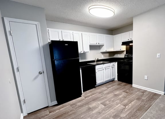 a kitchen with white cabinets and black appliances