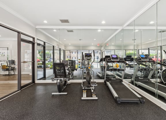 a gym with cardio equipment and glass walls