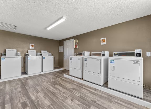 a row of washers and dryers in a laundry room with wood floors