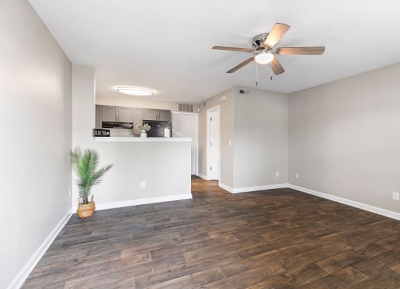 an empty living room with a ceiling fan and a kitchen
