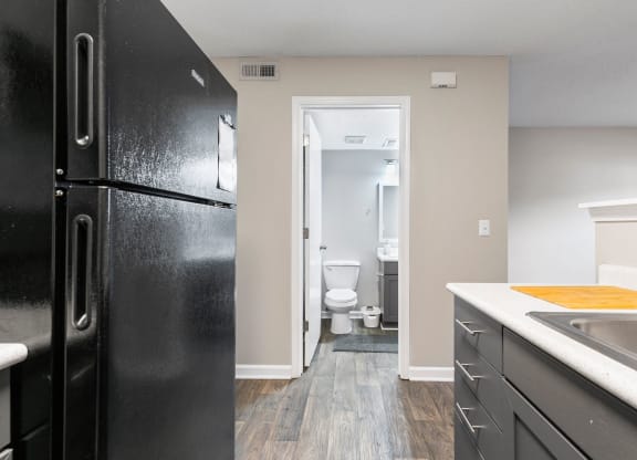 a kitchen with black appliances and a black refrigerator and a bathroom with a toilet