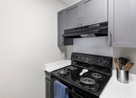 a kitchen with a stove and a microwave and white cabinets