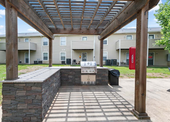 a covered patio with a grill in front of an apartment building