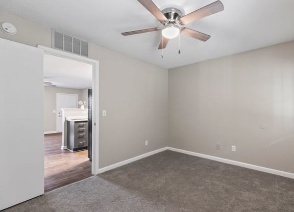 an empty living room with a ceiling fan
