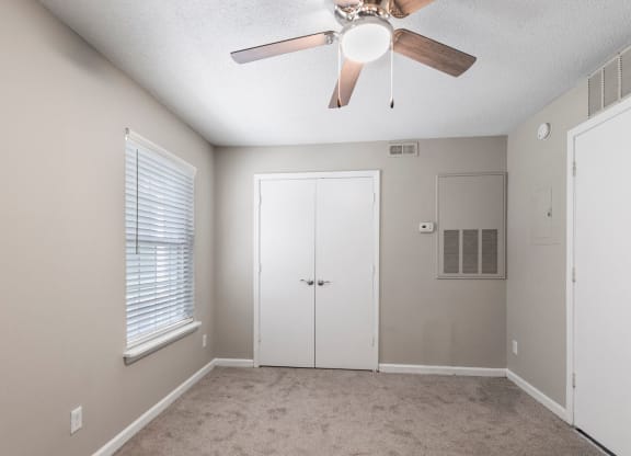 an empty bedroom with a ceiling fan and a closet