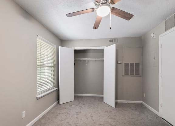 an empty bedroom with a ceiling fan and a closet