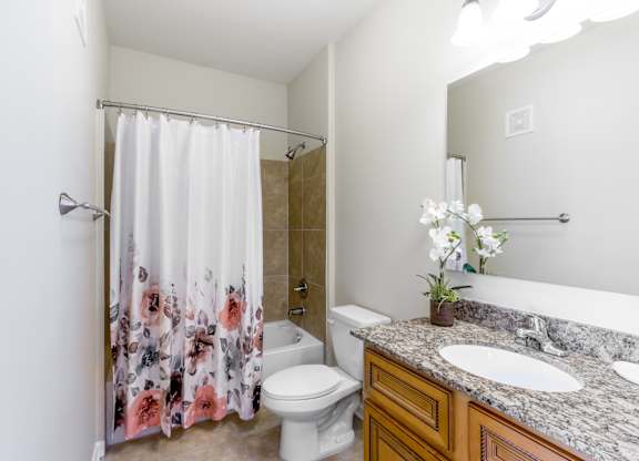A bathroom with a floral shower curtain and a marble countertop.