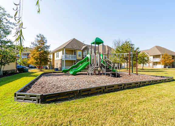 A playground with a green slide and a wooden structure.