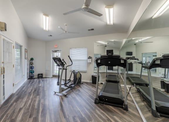 an exercise room with treadmills and a ceiling fan