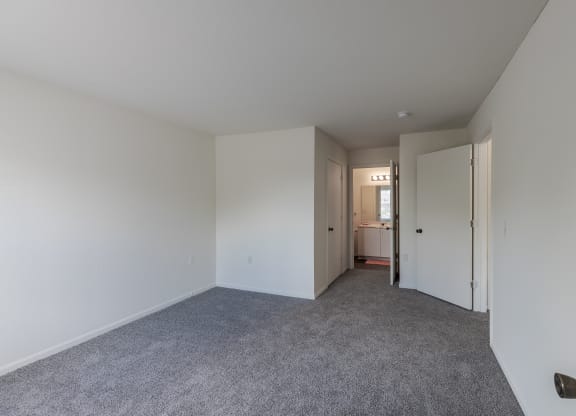A room with white walls and a grey carpet.