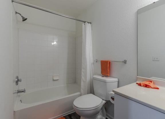 A white bathroom with a toilet, sink, and shower.
