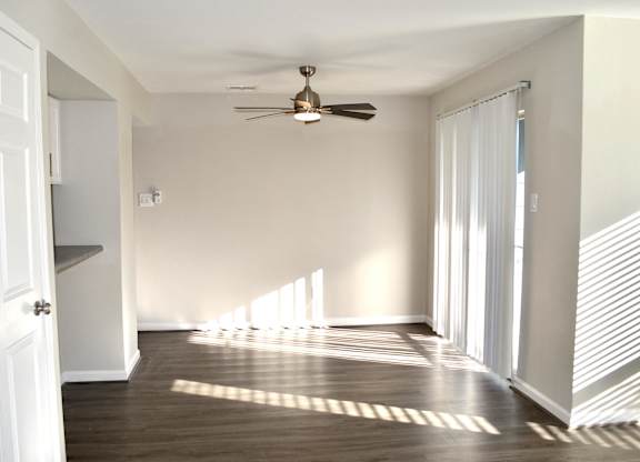 A room with a ceiling fan and wooden flooring.
