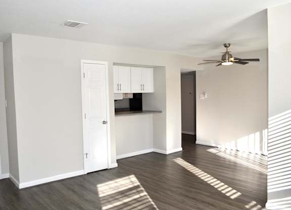 A room with a ceiling fan and a kitchenette.