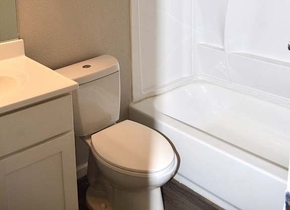 A white toilet sits in a bathroom next to a bathtub.