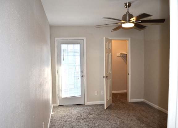A room with a ceiling fan and two doors, one of which is open.