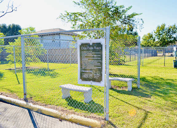 A sign in a fenced area with a bench underneath it.