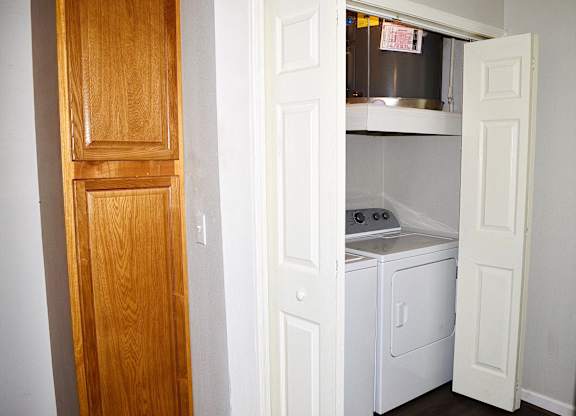 A white door is open to a small kitchen with a washer and dryer.