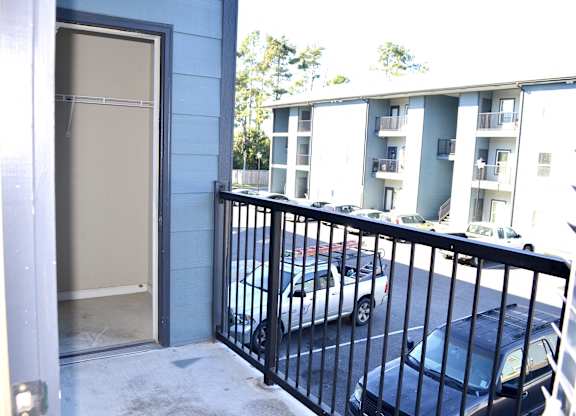 A car is parked on the street behind a black fence.