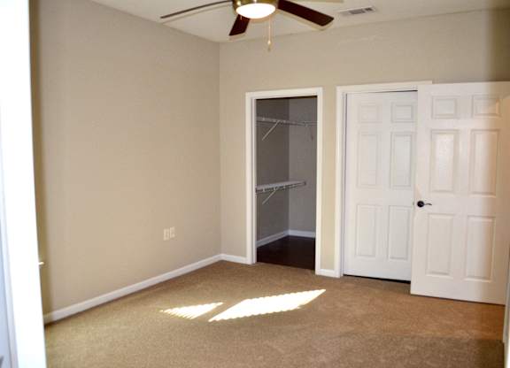 A room with a ceiling fan and two doors.