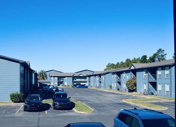 A parking lot with cars and apartment buildings in the background.