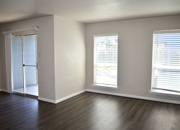 A room with a sliding glass door and two windows with blinds.