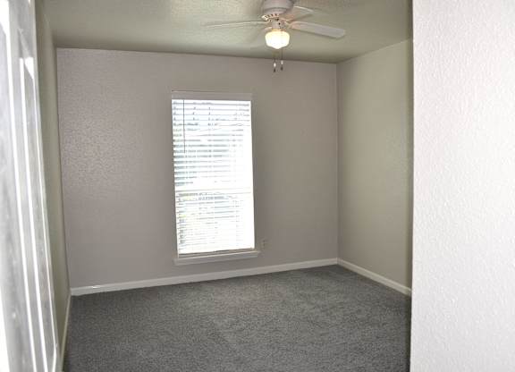 A room with a window covered by blinds and a ceiling fan.