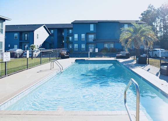 A swimming pool in front of a blue building.