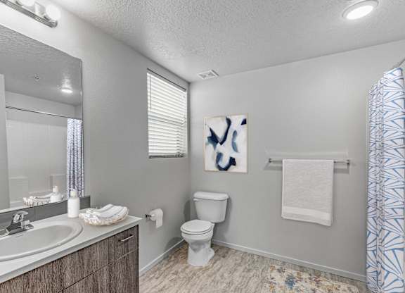 A bathroom with a toilet, sink, and a painting on the wall.