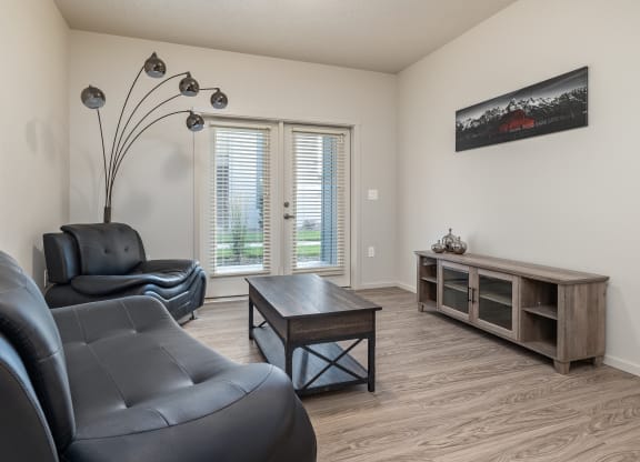 A living room with black leather chairs and a wooden coffee table.