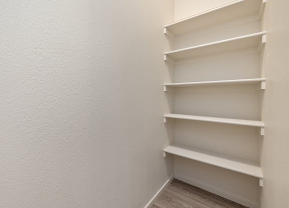 Empty white shelves in a corner of a room.