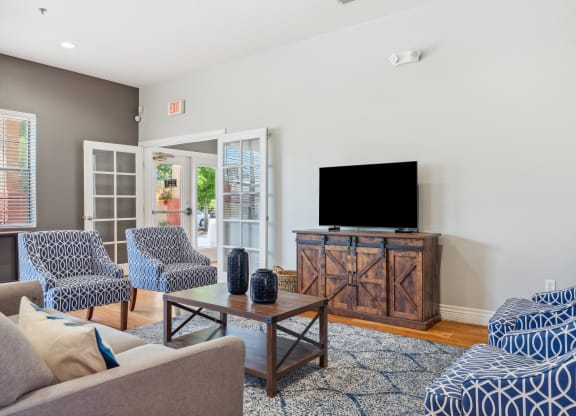 A living room with a grey couch, a blue patterned couch, a wooden cabinet, and a television.
