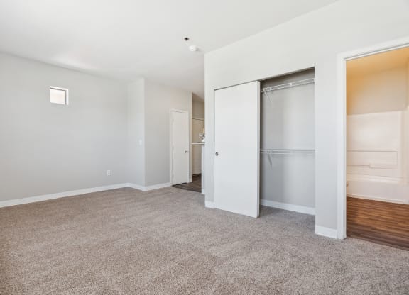 A spacious living room with a white door and a grey carpet.