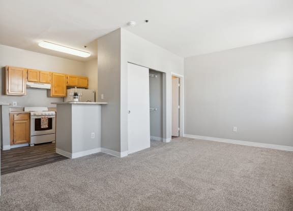 an empty living room and kitchen with white walls and carpet