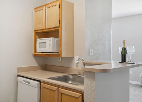 a kitchen with a sink and microwave and wooden cabinets