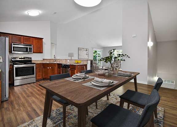 A modern kitchen with a wooden table set for two.
