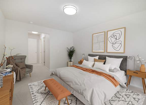 A bedroom with a bed, chair, and two framed artworks on the wall.