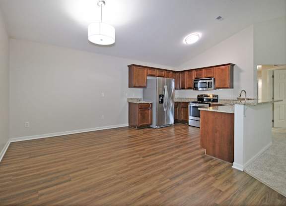 A kitchen with wooden cabinets and a stainless steel refrigerator.