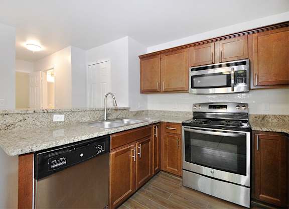 A kitchen with a stove, oven, sink and cabinets.