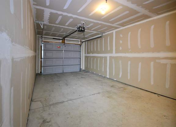 A garage with a grey door and a concrete floor.