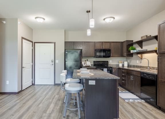 an open kitchen with a large island with bar stools and a refrigerator