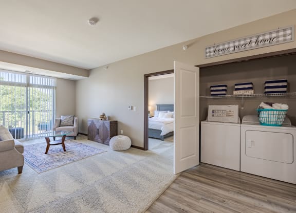 a laundry room with a washer and dryer and a bedroom in the background