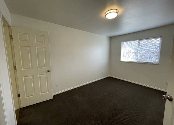A room with a door, a window, and a light on the ceiling.