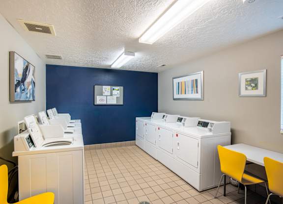 A room with a white desk and yellow chairs.