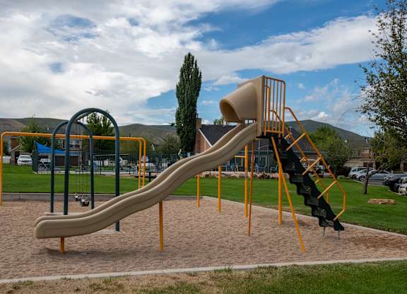 A playground with a yellow slide and a climbing frame.
