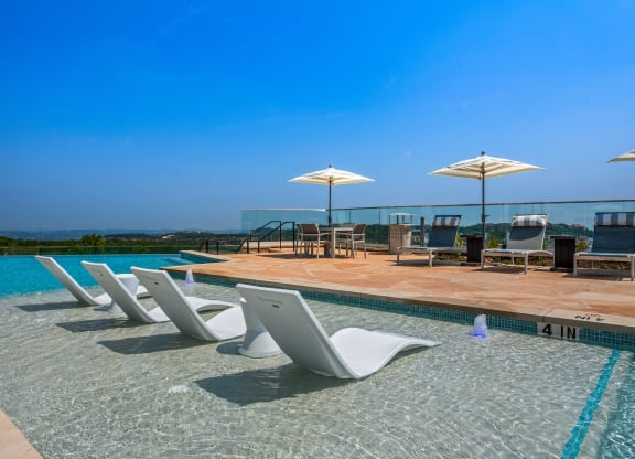 a swimming pool with chairs and umbrellas at a hotel