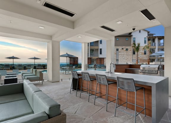 a kitchen with a bar and chairs in front of a beach view