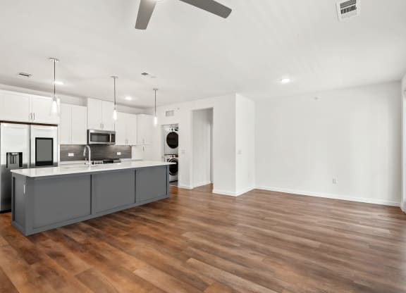 an open kitchen and living room with a wood floor and white walls